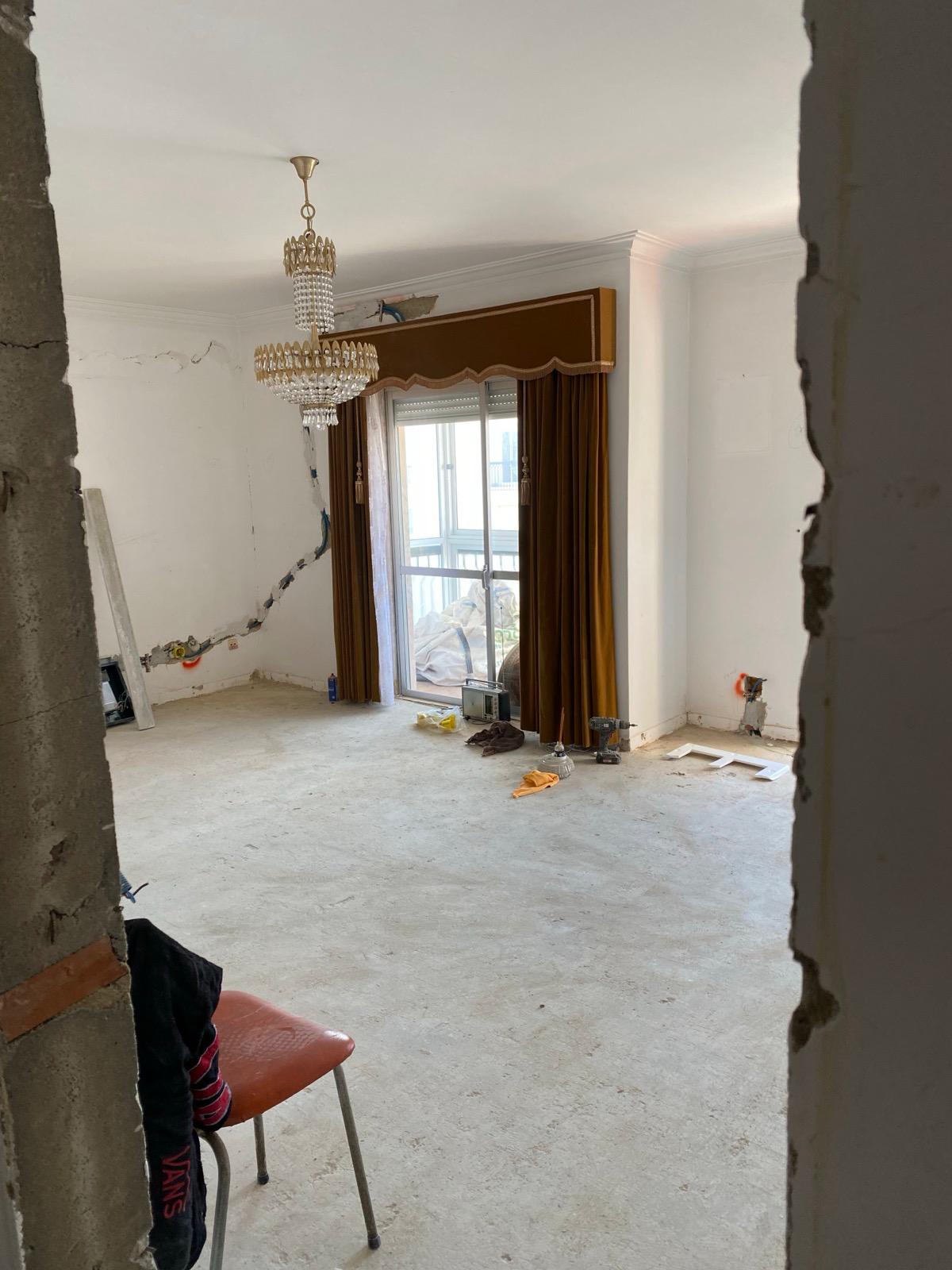 Antes: sala vazia com candelabro antigo, paredes a precisar de pintura e chão por nivelar.