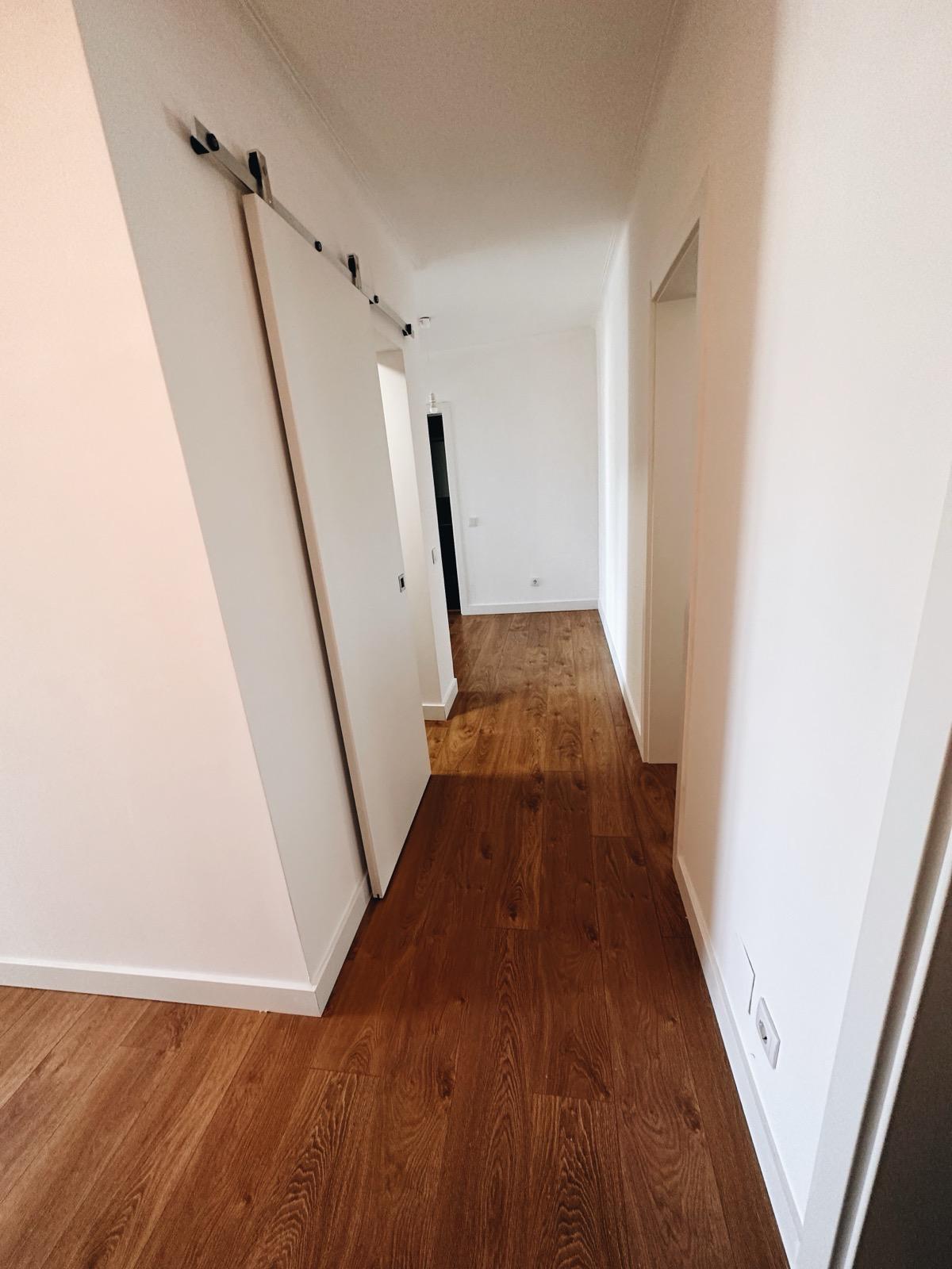 Depois: sala renovada com tecto rebaixado, iluminação encastrada e soalho flutuante.